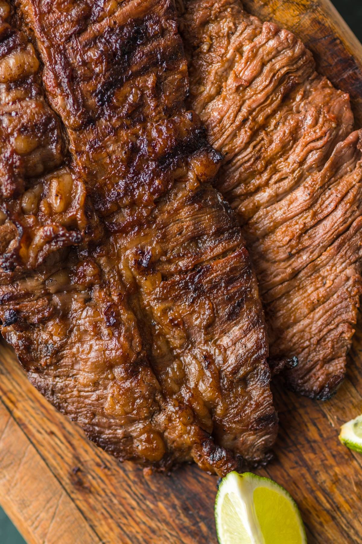 Grilled skirt steak on a wooden board with a lime wedge—perfect for anyone searching for the Best flank steak marinade or wondering how to make carne asada at home.