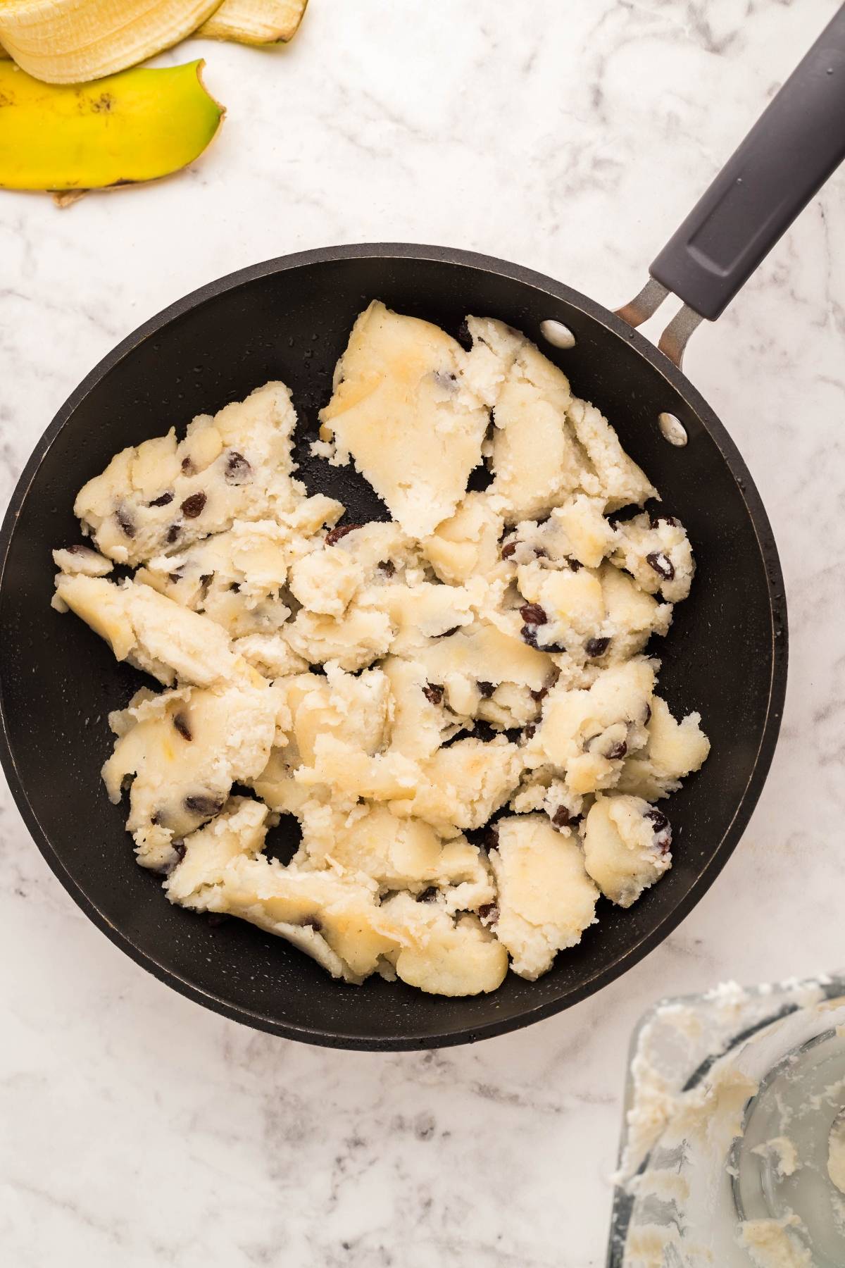 A frying pan with chunks of chocolate chip cookie dough on a marble countertop, perfect for turning into a gluten free dessert pancake inspired by Gluten Free Kaiserschmarrn.