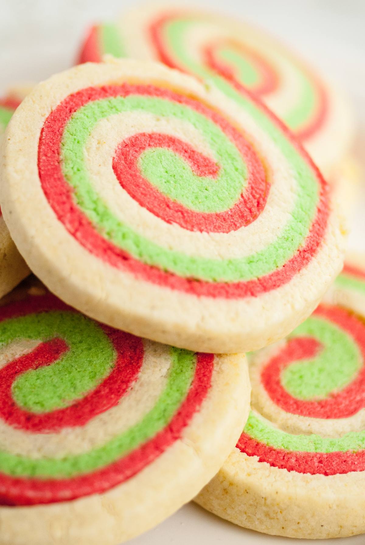 Round Gluten Free Pinwheel Cookies with red, green, and white swirl patterns are stacked closely together, perfect for festive gluten free holiday baking.