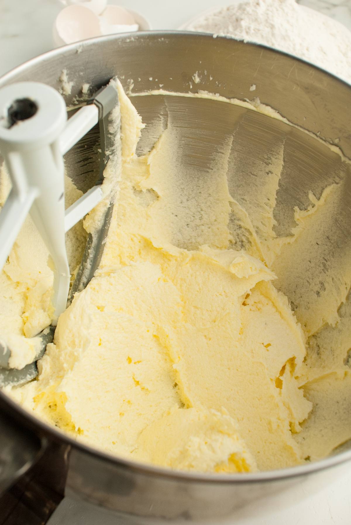 Creamed butter and sugar in a metal mixing bowl with a paddle attachment—the perfect base for making festive Italian Christmas swirl cookies.