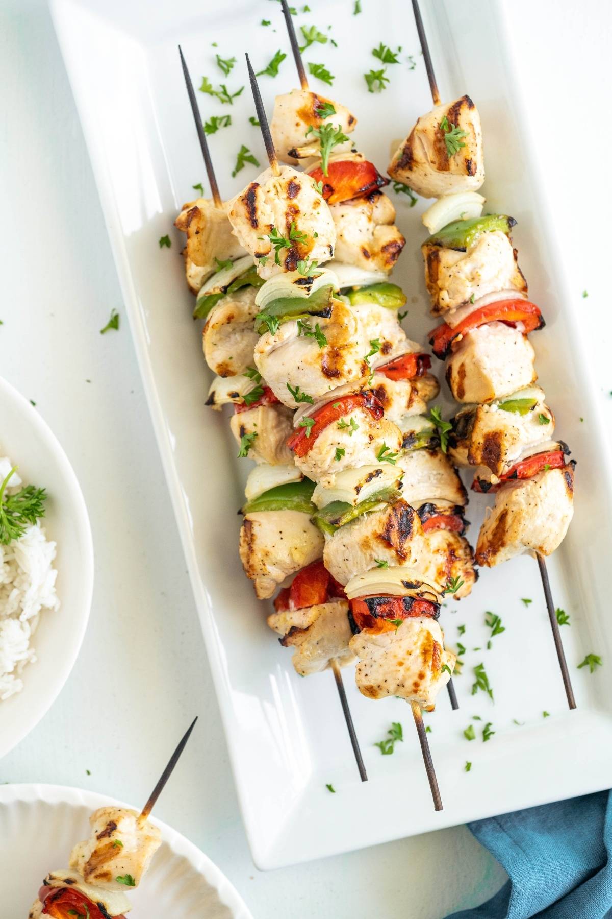 Grilled pepper and chicken kebabs are served on a white plate, garnished with chopped herbs—perfect for your next summer BBQ dinner.