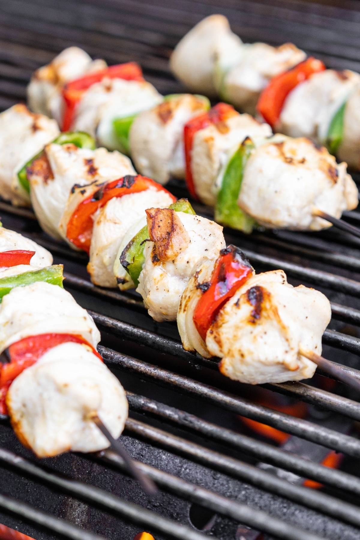 Tasty chicken skewers and vegetables grilling on a barbecue, with visible char marks—perfect for your next Summer BBQ dinner.