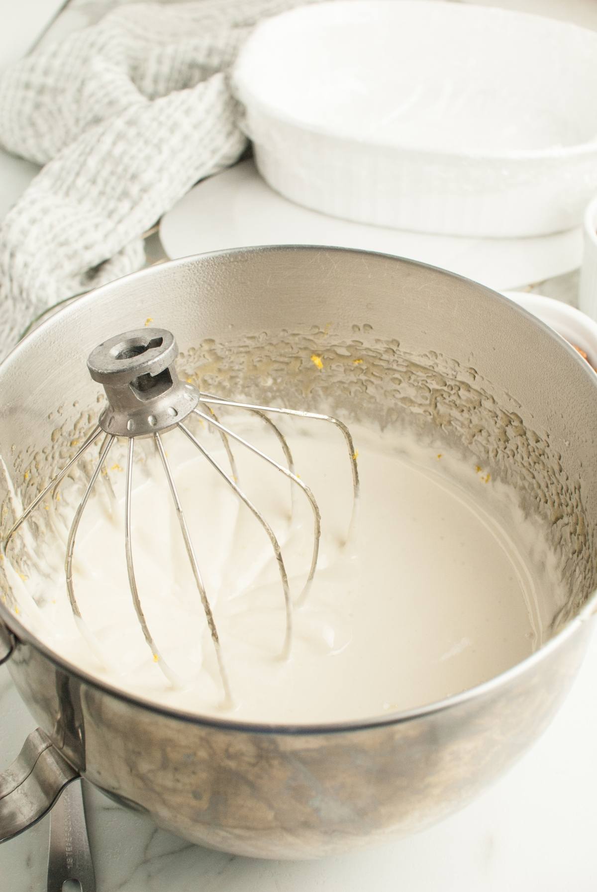 A metal mixing bowl with a whisk attachment and creamy batter inside, perfect for making homemade Torrone Italian Nut Nougat on your kitchen counter.