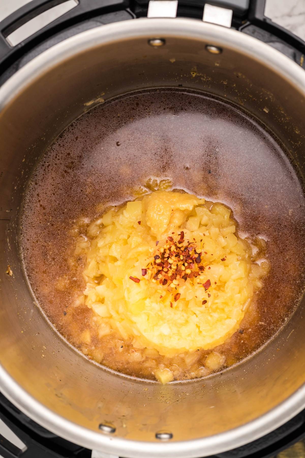 Chopped onions, broth, and spices in an Instant Pot—perfect for an easy Instant Pot dinner recipe or a delicious Instant Pot Hawaiian pork tenderloin.