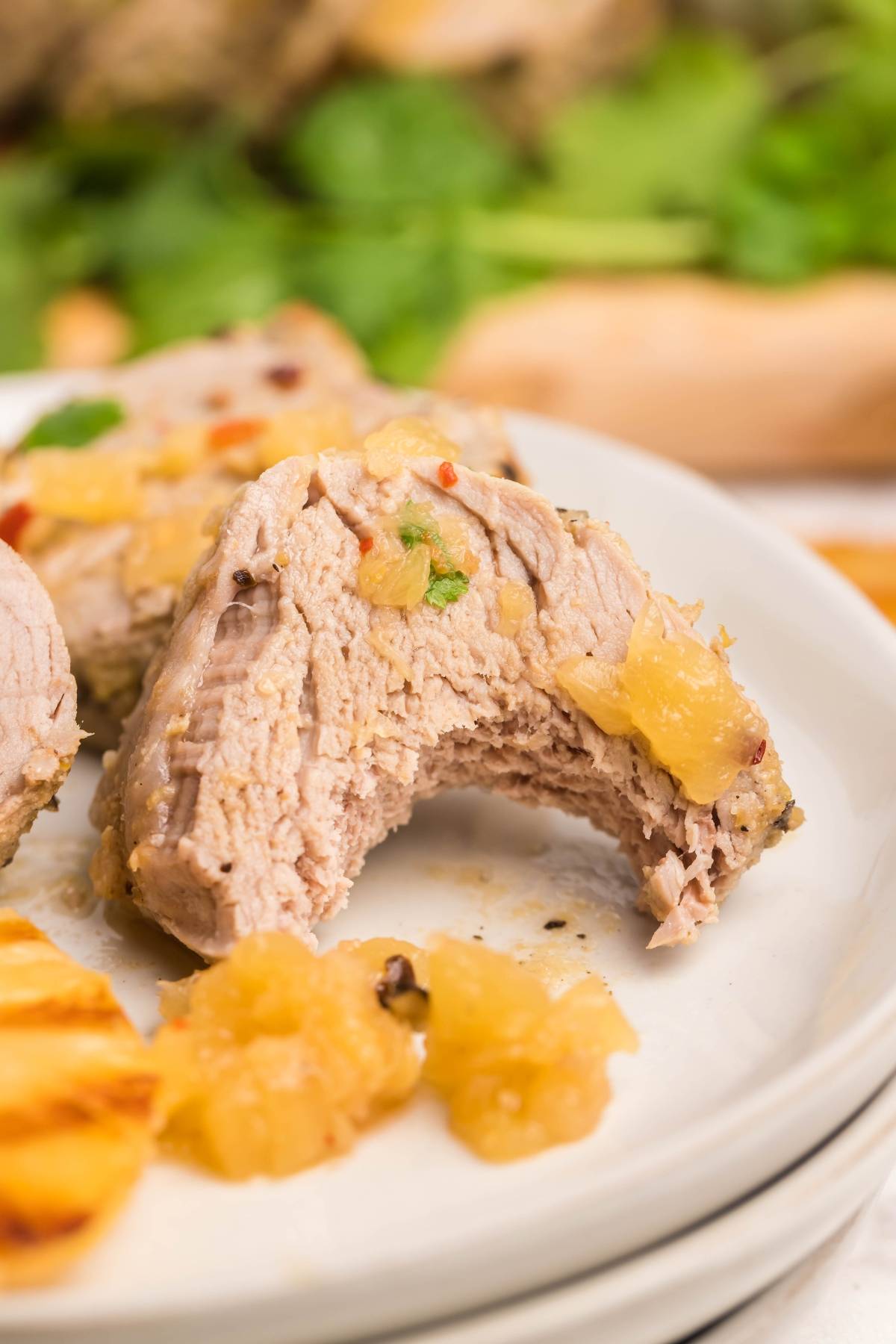 A piece of cooked pork with pineapple sauce, showing a bite taken out, on a white plate—perfect for showcasing your Instant Pot Hawaiian pork tenderloin or any Hawaiian inspired recipe.