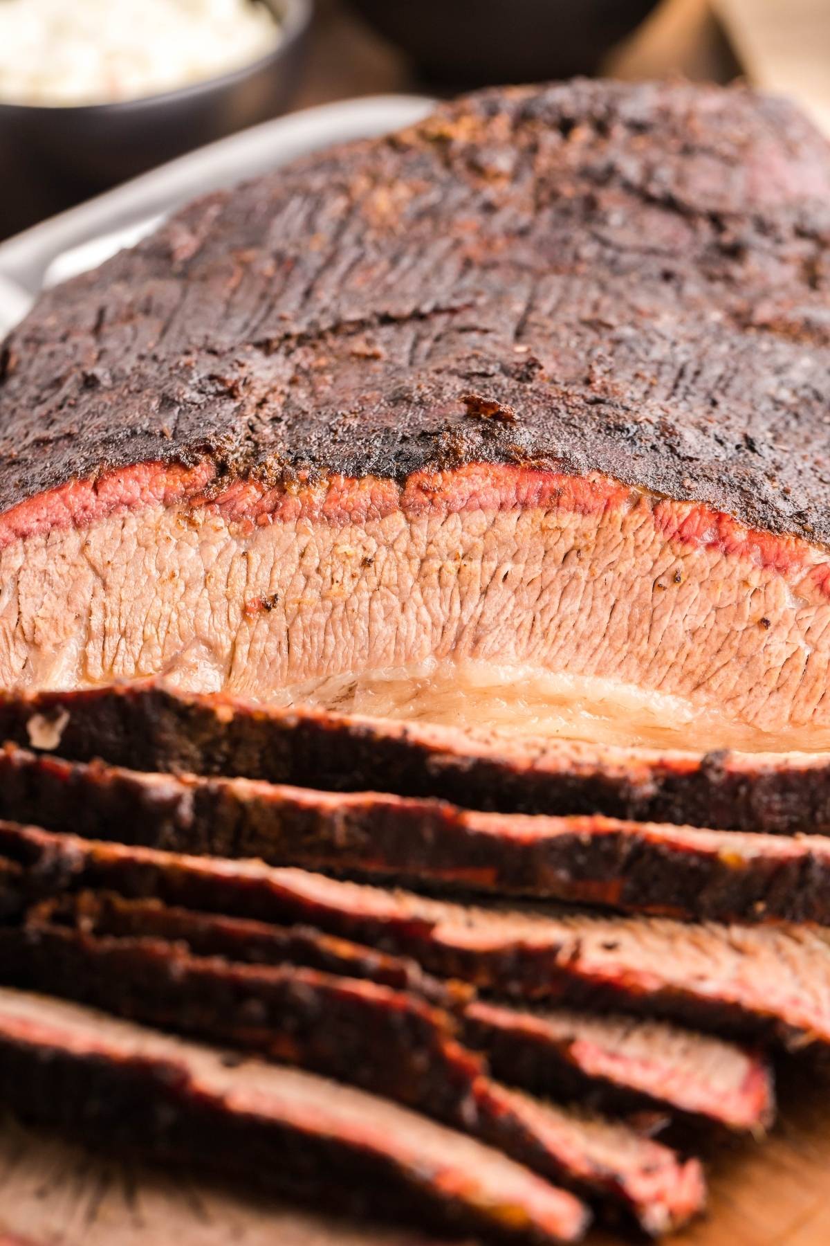 Sliced mesquite smoked brisket showing a juicy, tender interior and a dark, seasoned outer crust.