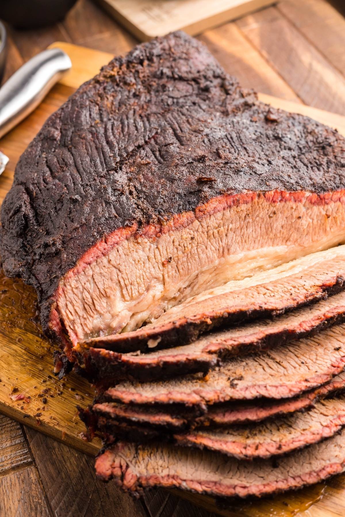 Sliced smoked brisket on a wooden cutting board, showing a dark crust and juicy interior made with a flavorful dry rub for brisket.