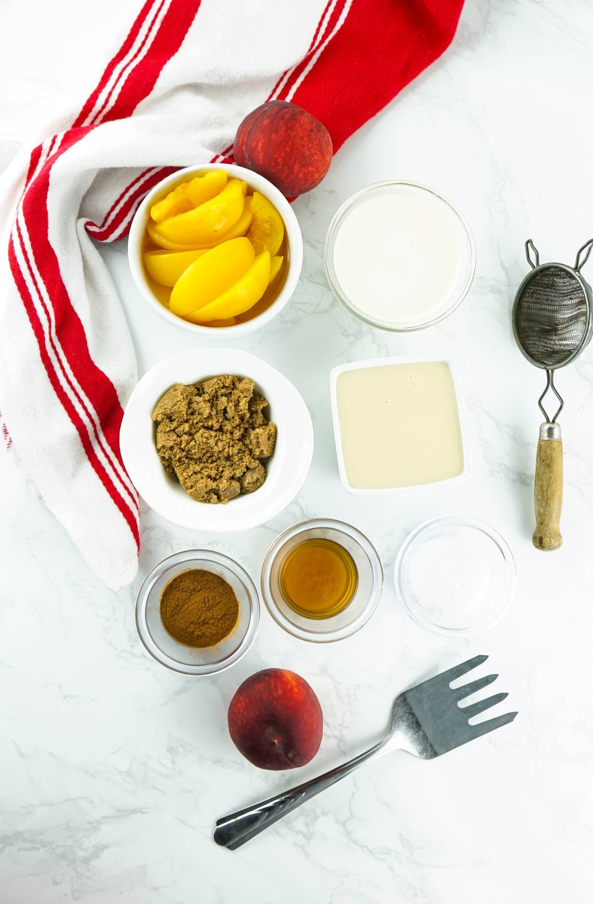 Ingredients for a recipe: cream, brown sugar, spices, vanilla, tofu, and kitchen tools on a white surface—perfect for making No Churn Bourbon Peach Ice Cream or another boozy peach dessert made with canned peaches.