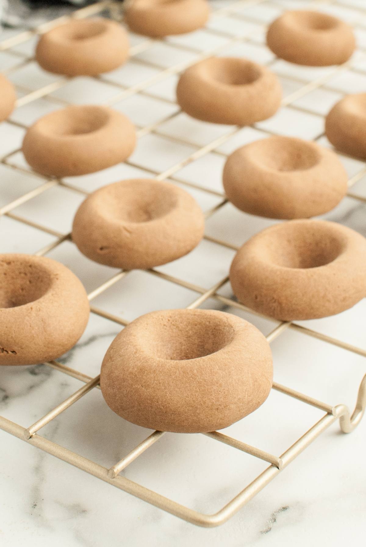 Round, light brown Nutellotti - Italian Nutella Cookies with thumbprint indentations cooling on a wire rack.