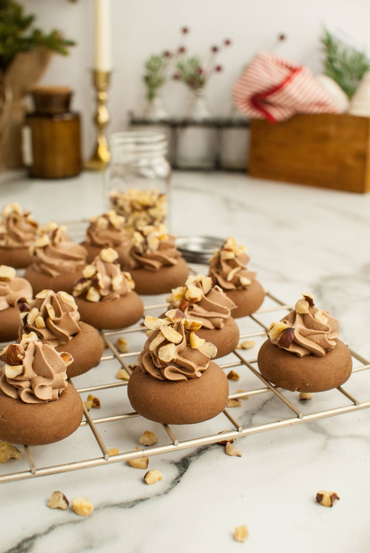 Chocolate cookies topped with chocolate frosting and chopped nuts on a cooling rack—these Nutella thumbprint cookies are perfect for festive kitchens and anyone looking for delicious recipes that use Nutella.