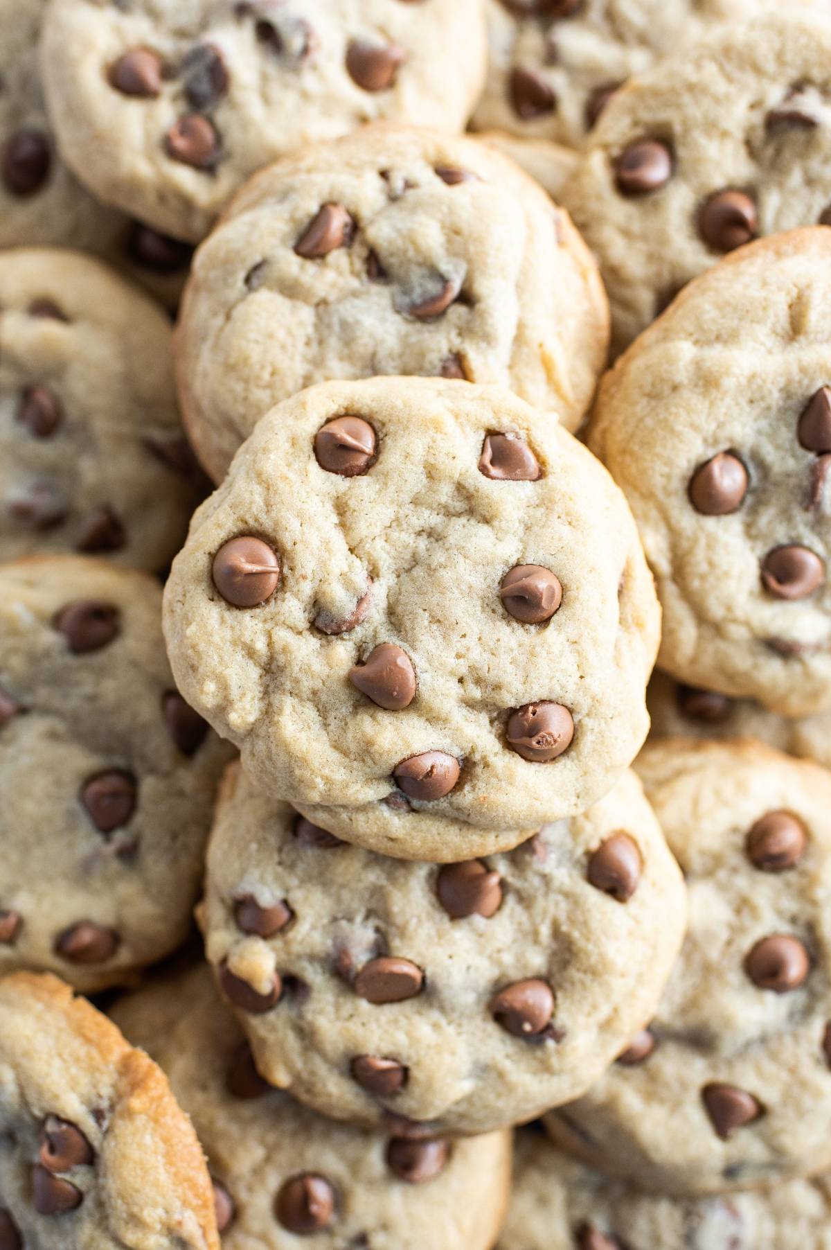 A close-up of several stuffed chocolate chip cookies stacked on top of each other, perfect for using leftover Halloween treats or making cookies with Reese’s in the middle.