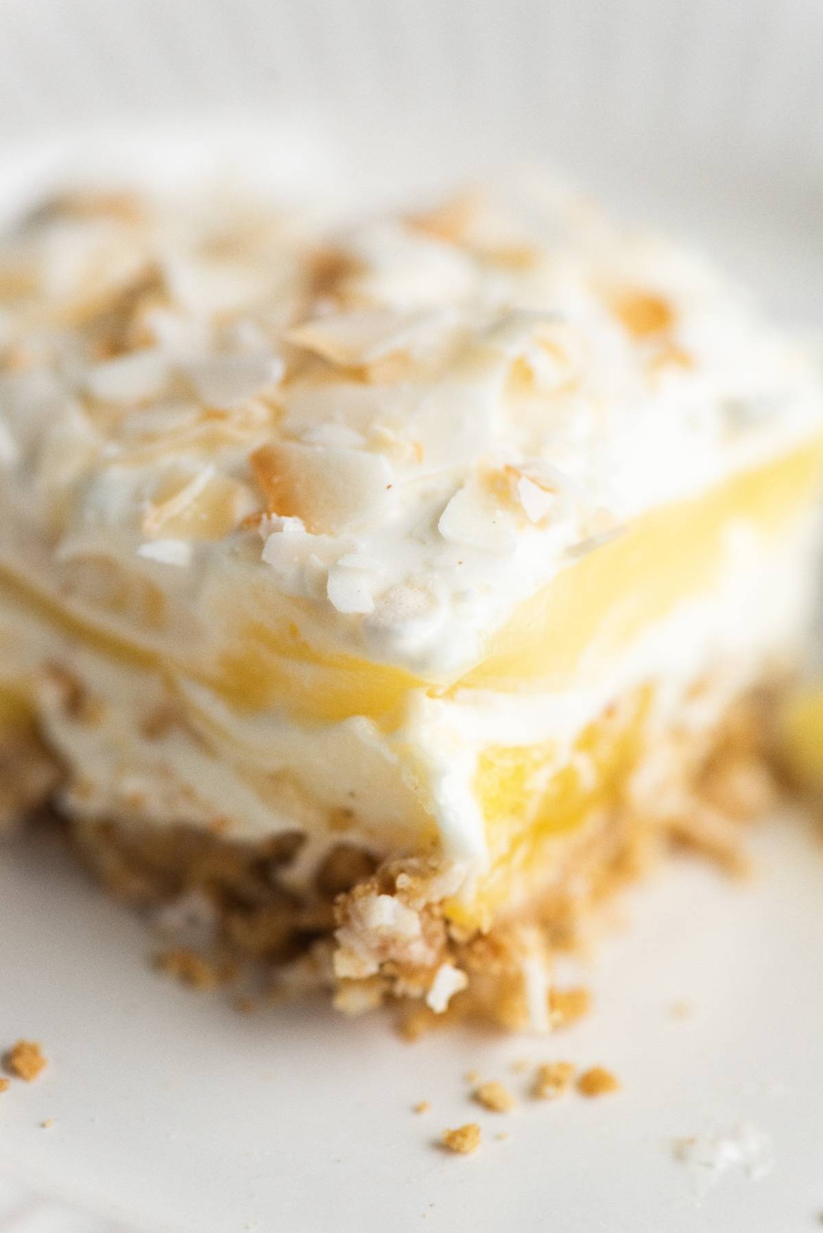 A close-up of a creamy lemon dessert bar with a crumbly crust and whipped topping—an irresistible creamy summer dessert that’s perfect for warm days.