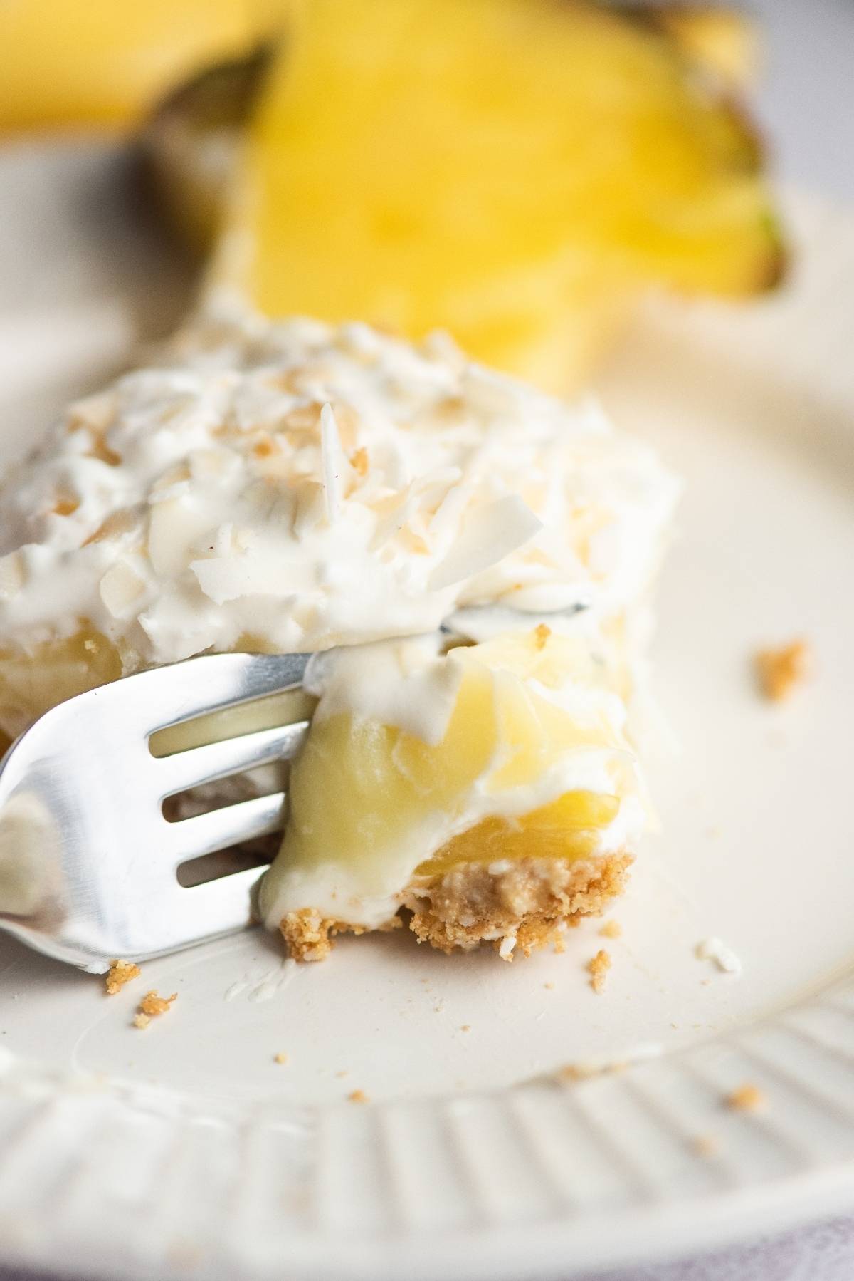 A fork cutting into a creamy, coconut-topped Hawaiian pineapple and coconut cake makes this dessert perfect for a summer BBQ.