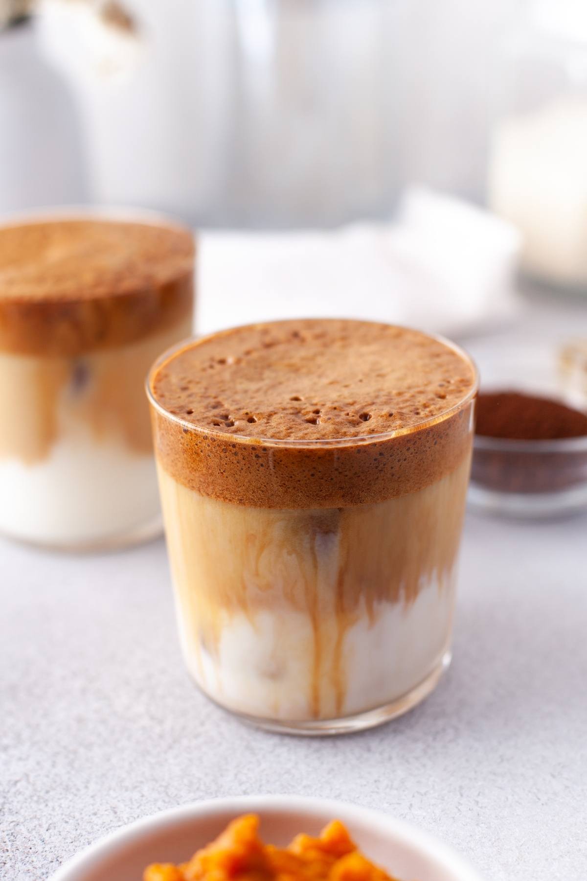 Iced Pumpkin Spice Whipped Dalgona Coffee with a fluffy pumpkin whipped coffee layer on top of milk in a clear glass, perfect for enjoying that cozy autumn coffee flavour.