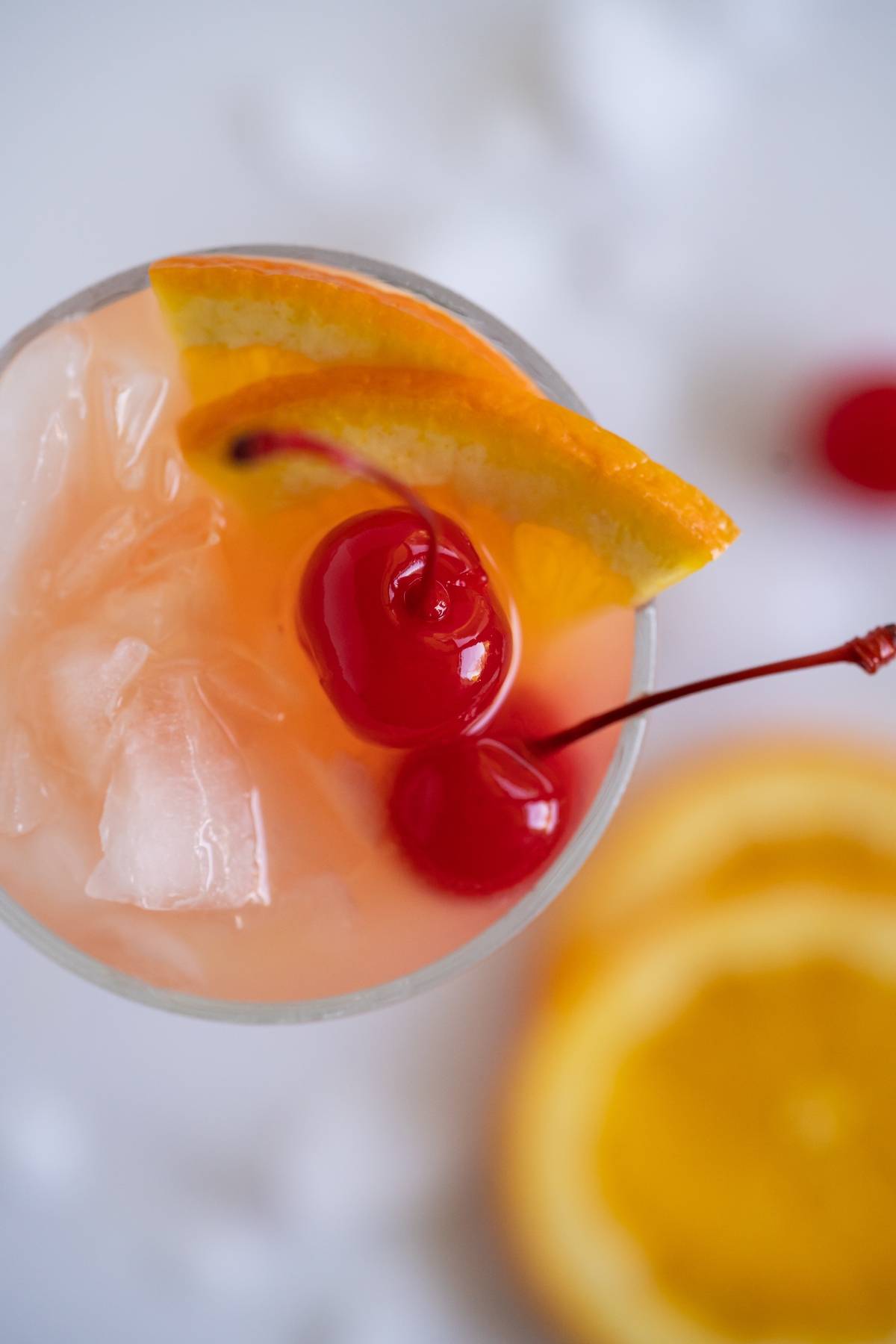 Close-up of a rum runner cocktail with ice, two maraschino cherries, and an orange slice garnish—perfect inspiration if you’re curious about how to make a rum runner or want to try a classic Caribbean punch cocktail recipe.