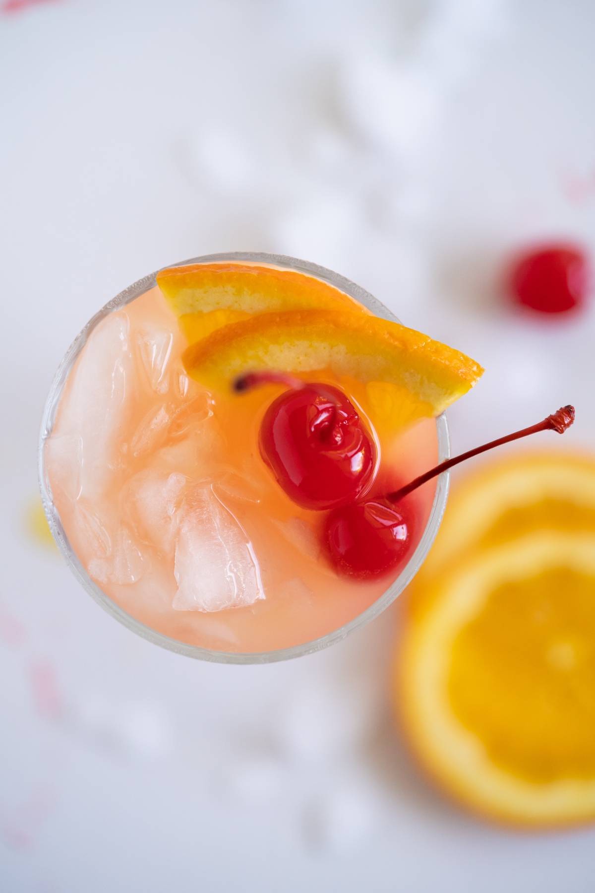 A cocktail with ice, orange slices, and two maraschino cherries, viewed from above—just like an Easy rum runner recipe.
