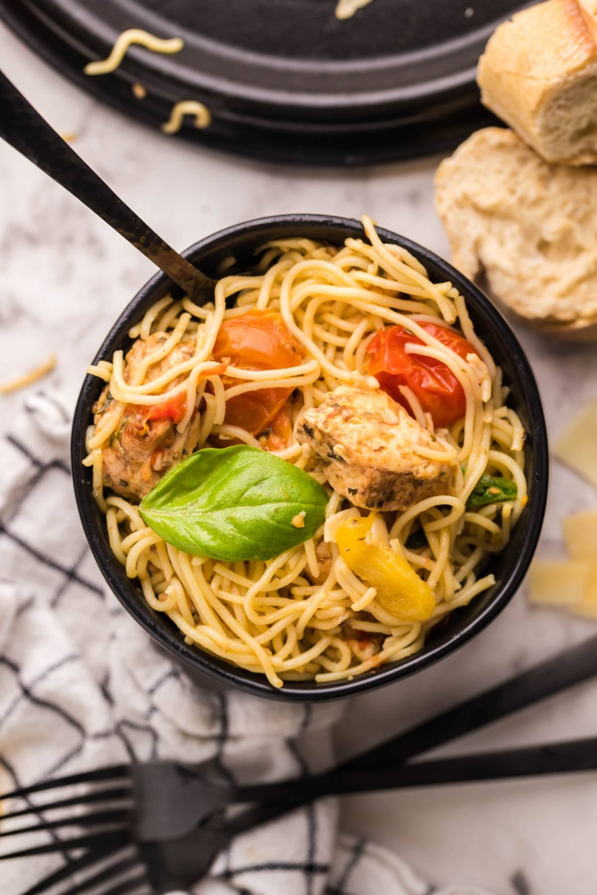 Bowl of spaghetti with tomatoes, basil, and bread on the side, inspired by Sheet Pan Chicken Caprese Pasta for an easy oven chicken caprese twist—viewed from above.