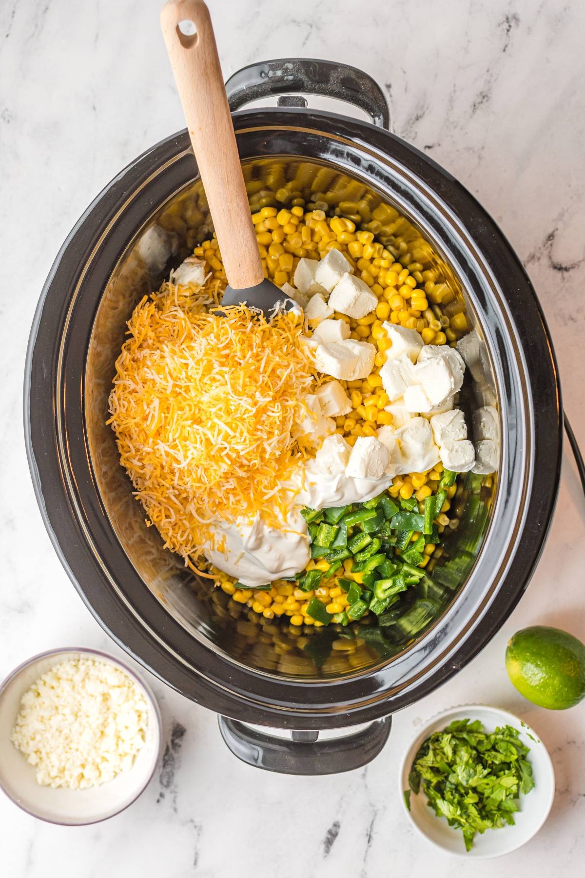 A slow cooker filled with corn, cream cheese, shredded cheese, green peppers, and sour cream—this cheesy Mexican-style appetizer is ready to mix and serve.
