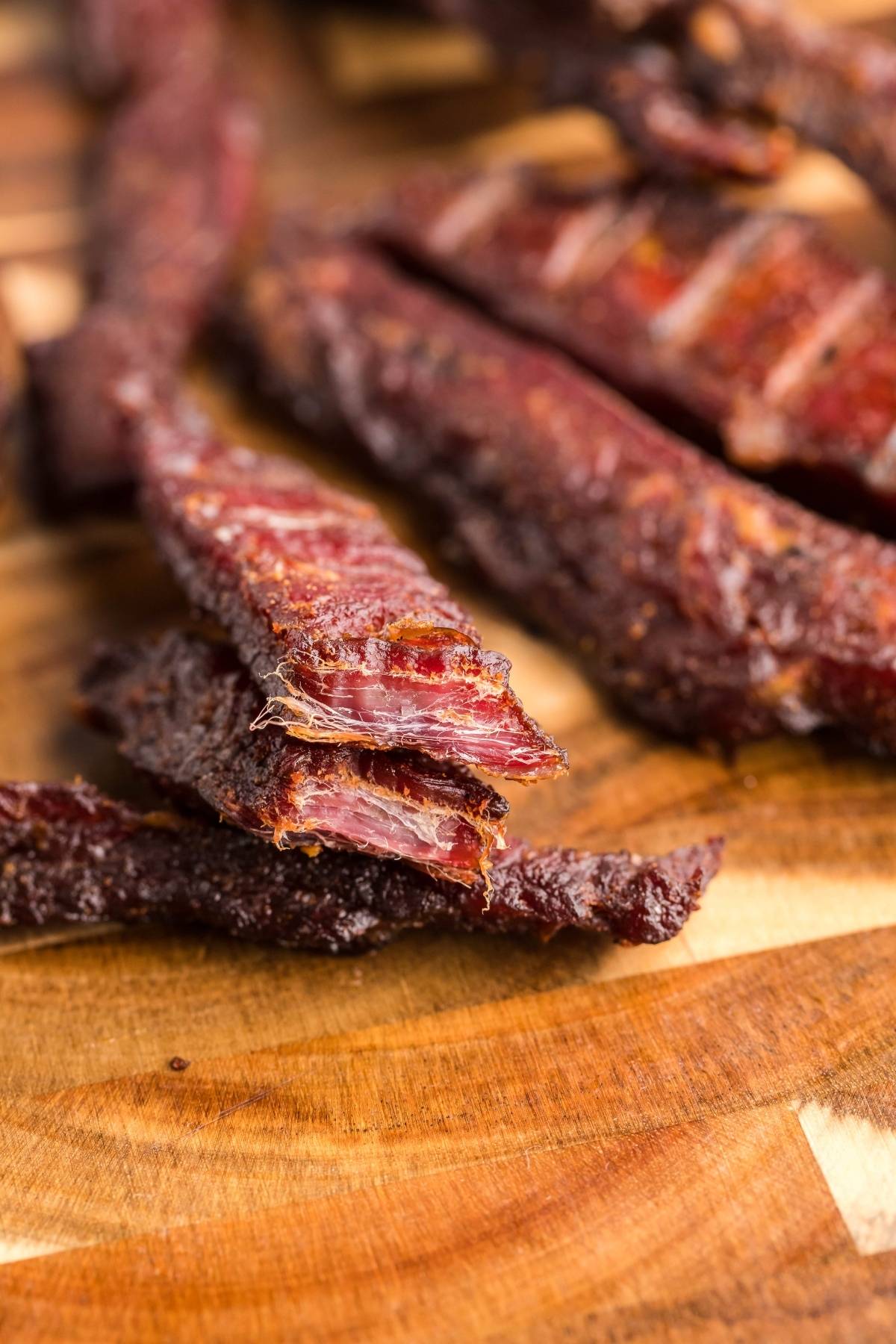 Close-up of smoked beef jerky strips stacked on a wooden surface, showcasing gluten free paleo jerky perfect for satisfying your savory cravings.