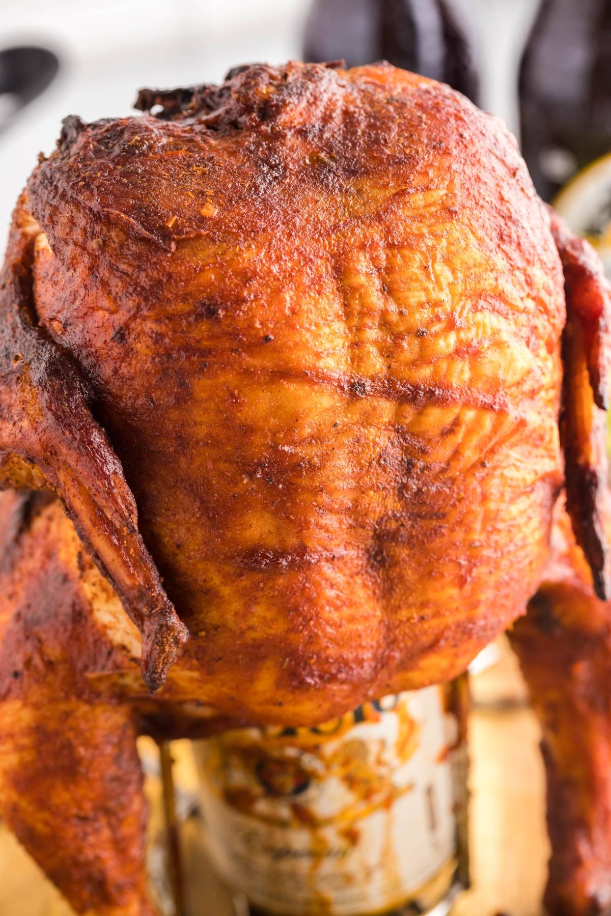 Golden roasted whole chicken sitting upright on a can, perfect for anyone wanting to make beer can chicken or try a flavorful Traeger beer can chicken grilled recipe.