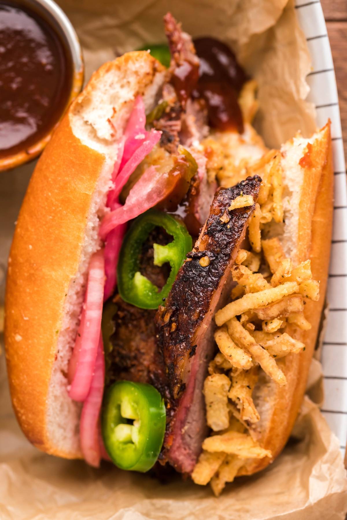 Smoked Brisket Sandwich with pickled onions, jalapeños, crispy onions, and sauce on a hoagie roll—perfect for those seeking delicious brisket sandwich toppings or a satisfying sandwich using leftover brisket.
