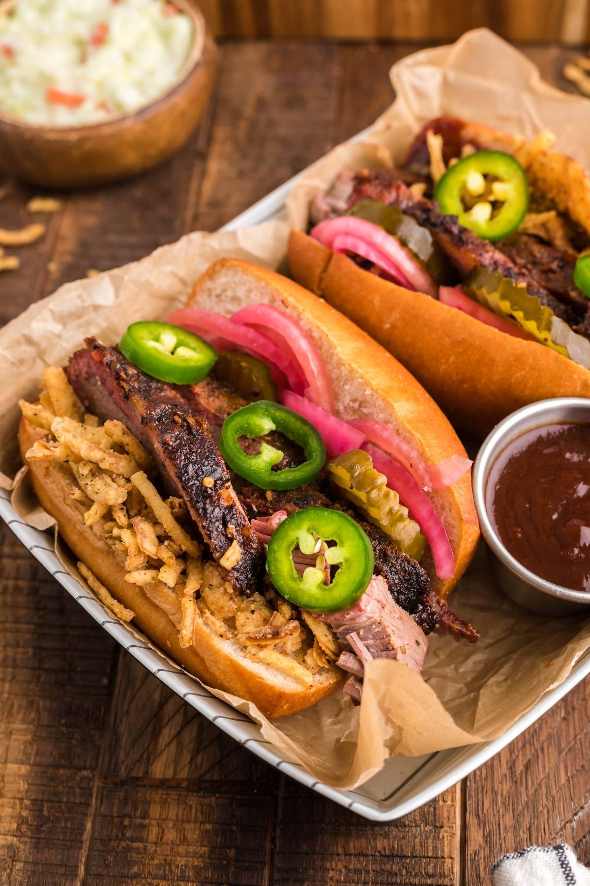 Enjoy our Best BBQ brisket sandwich—two sandwiches using leftover brisket, packed with classic brisket sandwich toppings like pickles, jalapeños, onions, and served with a side of barbecue sauce.