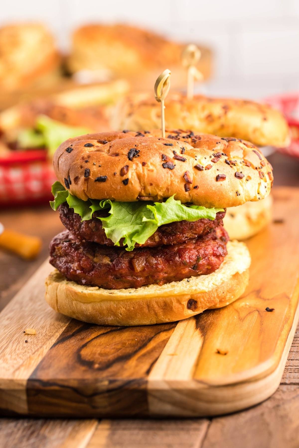 A double beef burger with lettuce on an onion bun, served on a wooden board—our smoked cheddar bacon stuffed burger is perfect for fans of bold flavors.