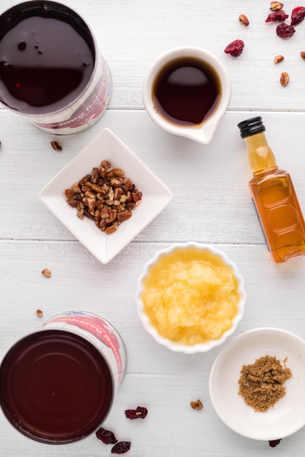Cranberry bourbon relish, vanilla, pecans, applesauce, oil, and brown sugar arranged on a white table.