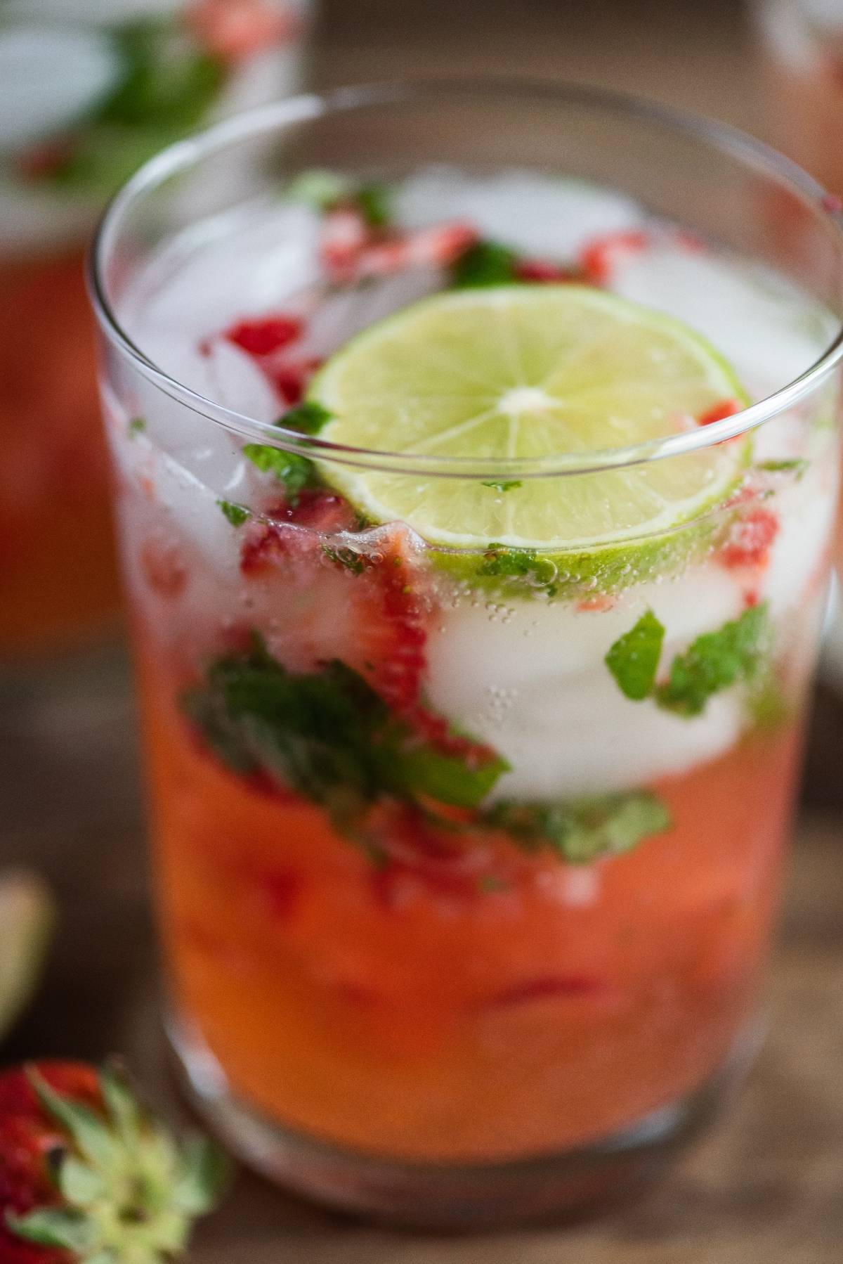 A refreshing cocktail with white rum, this iced strawberry mojito is garnished with lime slices and fresh mint leaves.