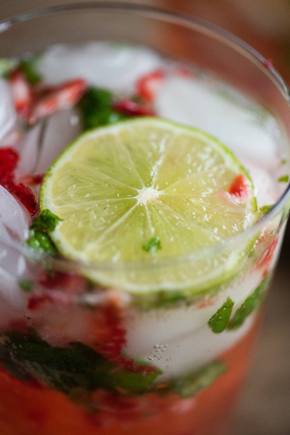 Close-up of a Strawberry mojito, a refreshing drink with ice, mint, strawberry pieces, cachaça or dark rum, and a slice of lime on top—an easy summer cocktail recipe perfect for warm days.
