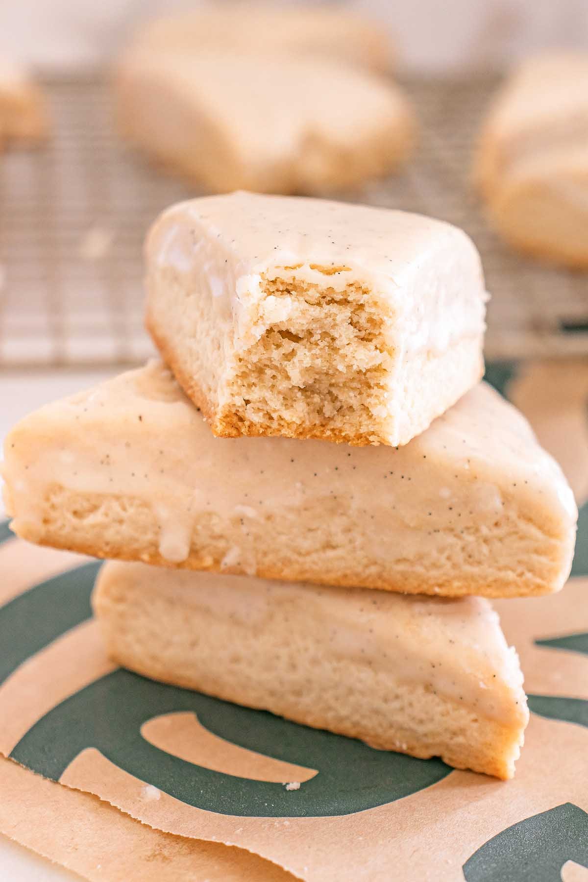 Three Starbucks Copycat Vanilla Bean Scones are stacked, with the top scone glazed and showing a bite taken out.