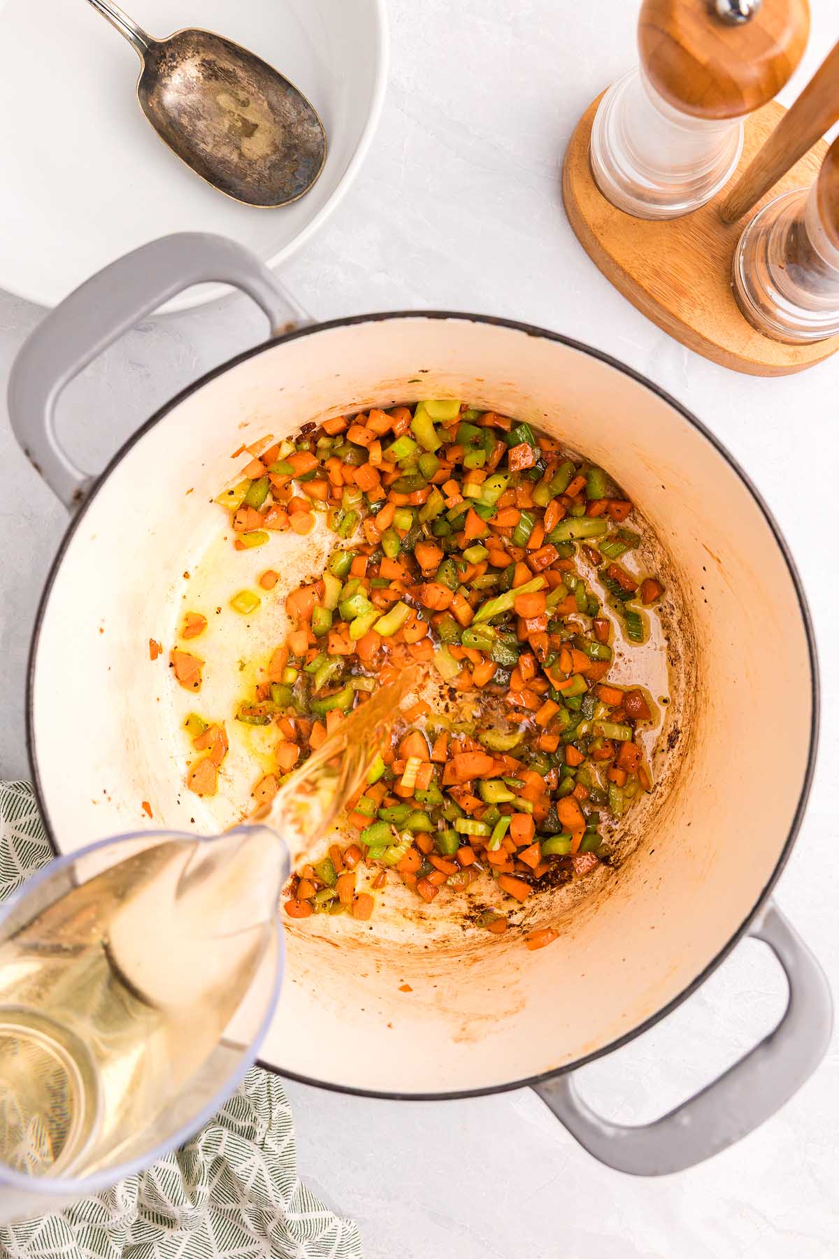 Wine is poured into a pot with saut&eacute;ed carrots, celery, and onions on the counter&mdash;classic steps in preparing pasta alla Genovese.