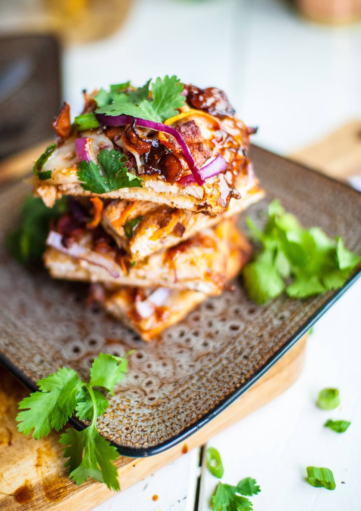 Stack of pizza slices topped with cilantro, red onion, and barbecue sauce—these BBQ Chicken Flatbread Pizzas are made in under 30 minutes for a quick and tasty meal.