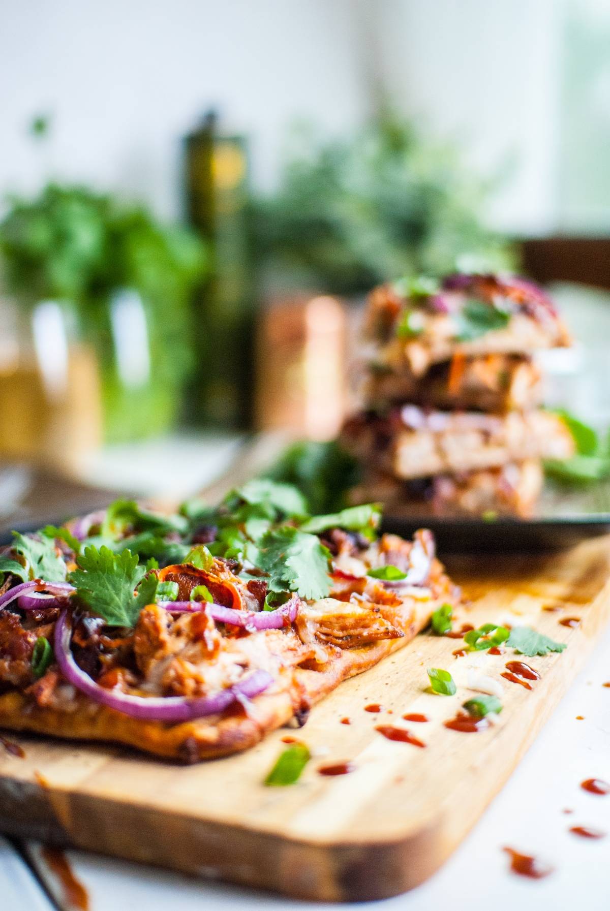 Close-up of BBQ pulled pork on bread, topped with red onions and cilantro, on a wooden board—deliciously inspired by barbecue chicken flatbread like Panera and made in under 30 minutes.