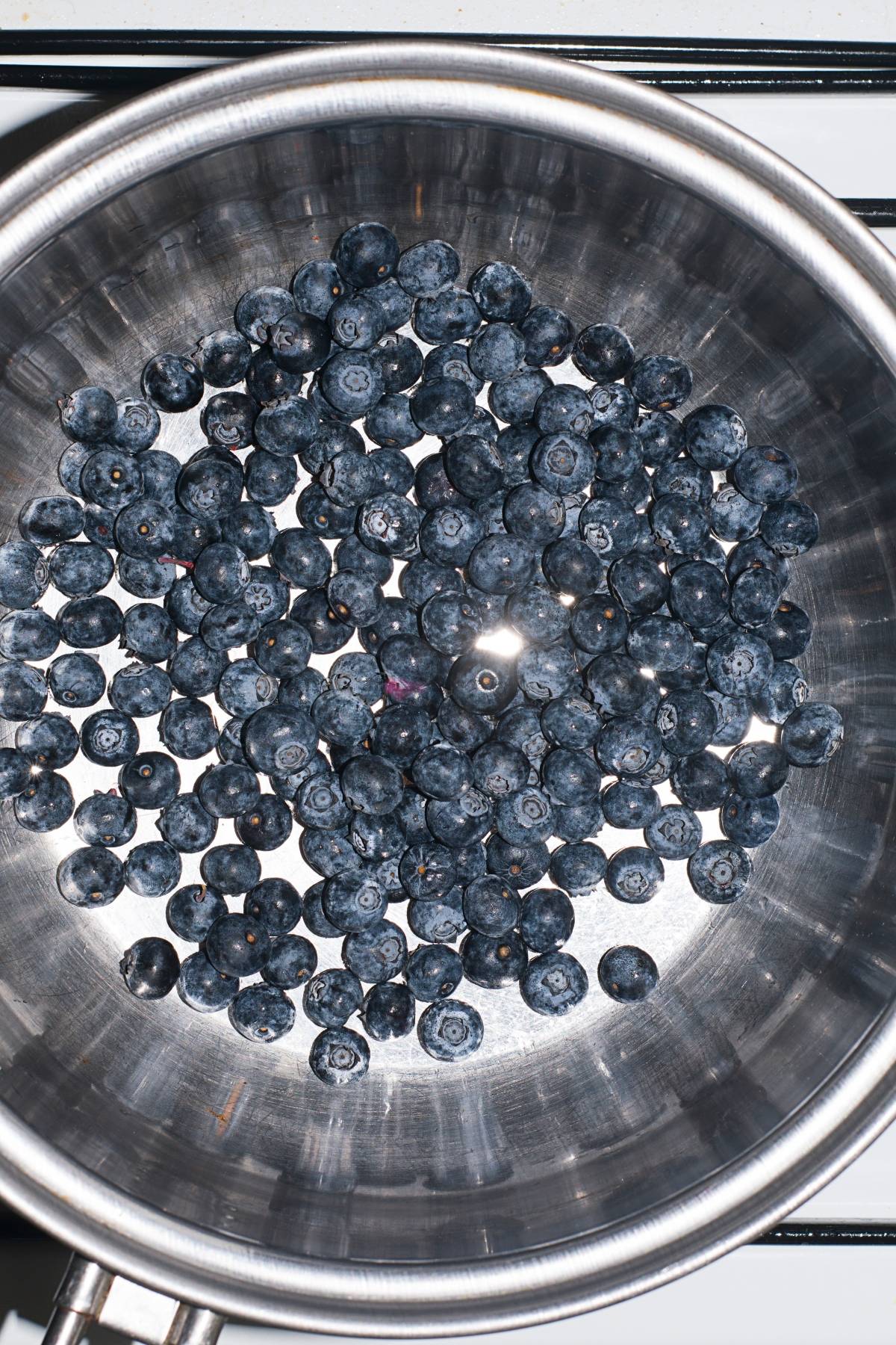 Blueberries scattered in a stainless steel pot on a stove, ready to inspire your next sparkling blueberry float or ice cream float recipe.