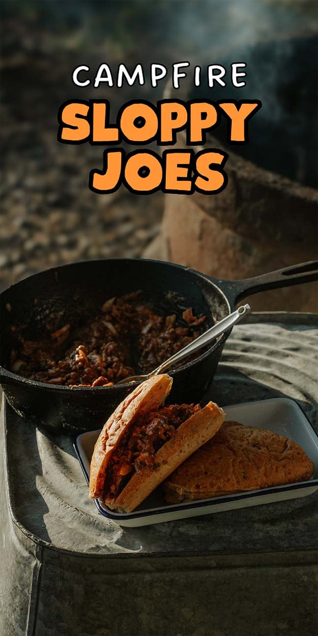 A skillet of sloppy joe mix and a sandwich on a plate beside a campfire, paired perfectly with a campfire marshmallow cocktail. Text reads "Campfire Sloppy Joes.