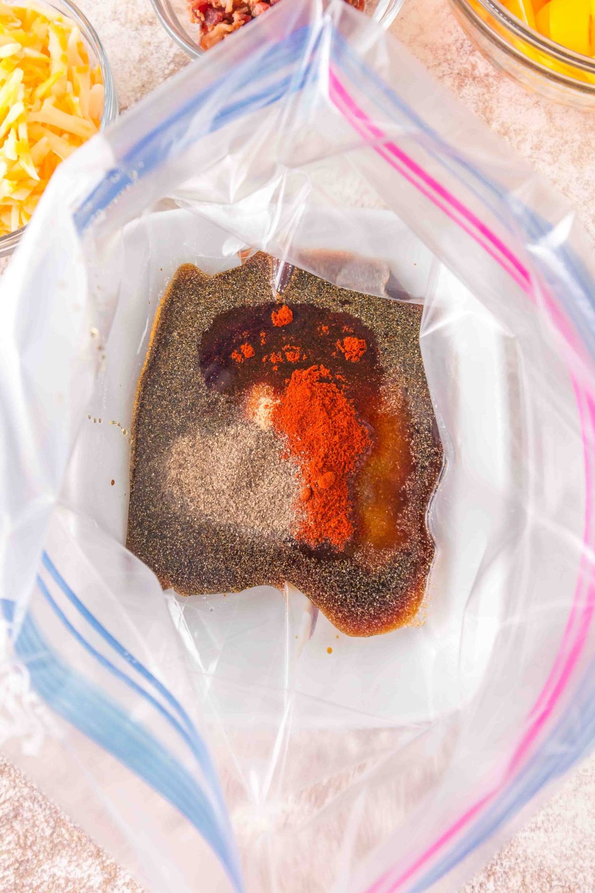 A plastic bag with spices, sauce, and marinade inside, surrounded by bowls of shredded cheese and other ingredients.