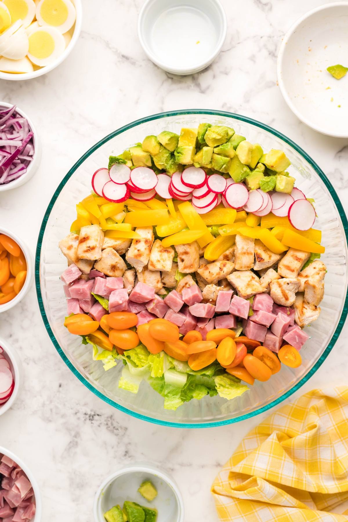 A filling dinner salad, this Cobb salad bowl features rows of ham, chicken, tomatoes, peppers, radishes, avocados, and crisp lettuce—a perfect recipe using leftover ham.