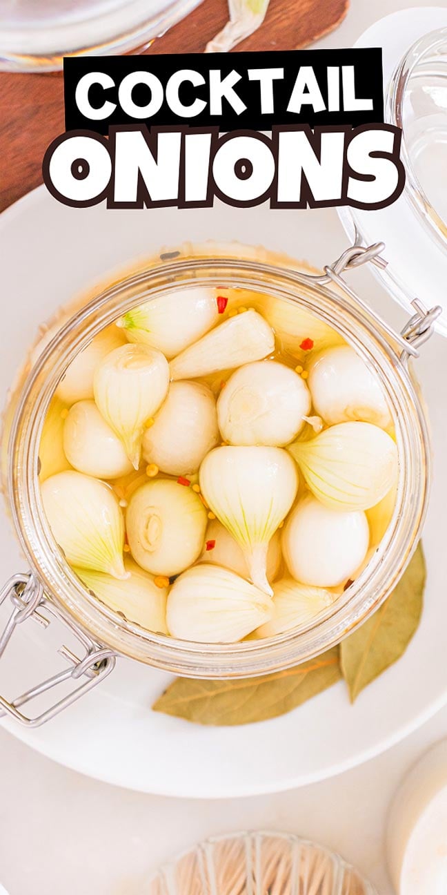 Glass jar of cocktail onions in brine, with spices and bay leaf on a white plate. These crisp cocktail onions add the perfect tangy crunch to your favorite drinks and appetizers. Text reads "COCKTAIL ONIONS.