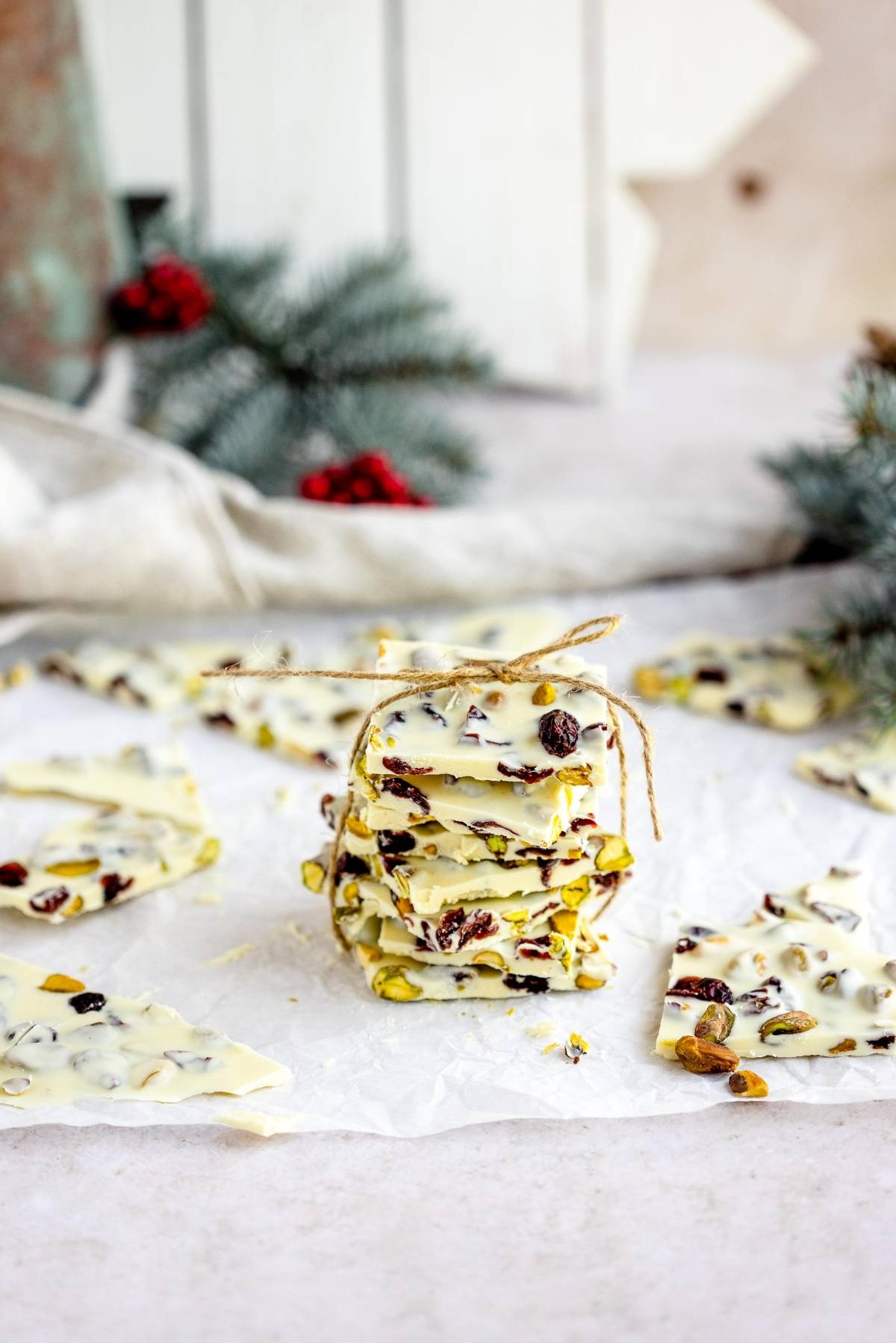 Stack of Cranberry Pistachio White Chocolate Bark, tied with twine on parchment paper—an easy holiday treat recipe featuring creamy white chocolate, tart cranberries, and crunchy pistachios.