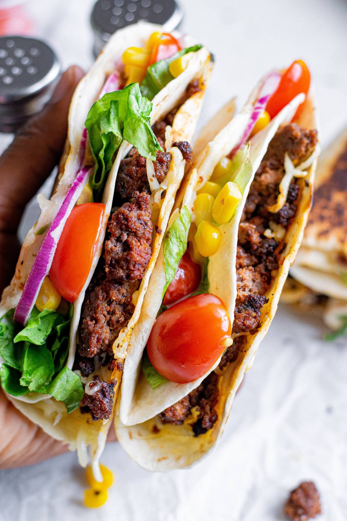 Two soft tacos filled with ground beef, lettuce, tomatoes, red onion, corn, and shredded cheese—our take on the TikTok folded tortilla trend for a delicious handheld meal.