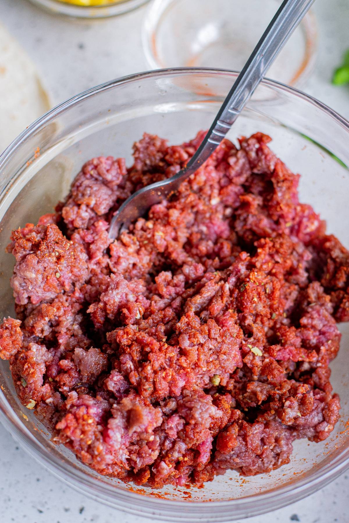 Ground beef mixed with spices in a glass bowl with a fork, perfect for creating the viral Tik Tok folded tortilla hack.