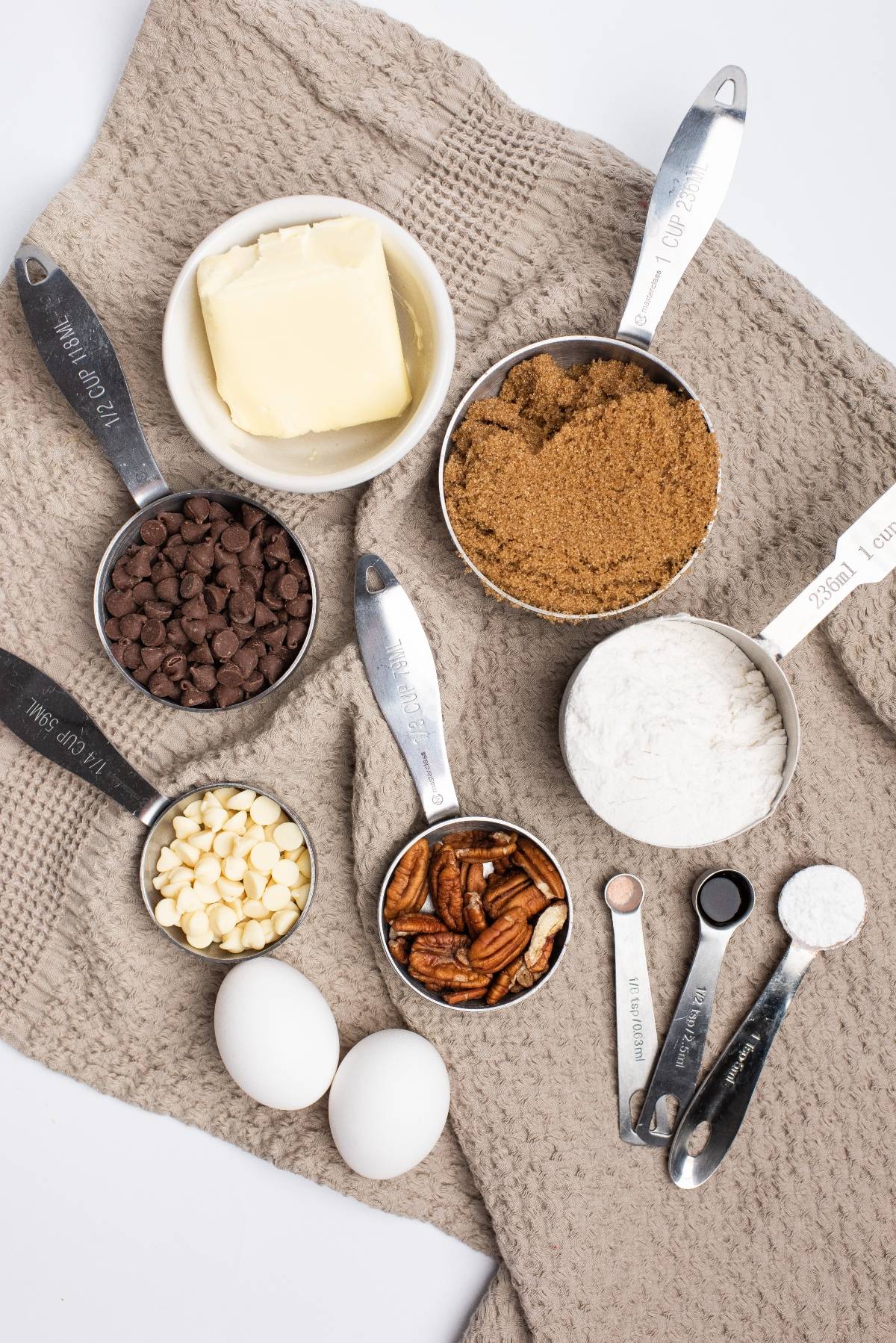 Baking ingredients including butter, brown sugar, flour, eggs, pecans, measuring spoons, and both semisweet and white chocolate—everything you need for an easy blondie recipe or Double Chocolate Pecan Blondies.