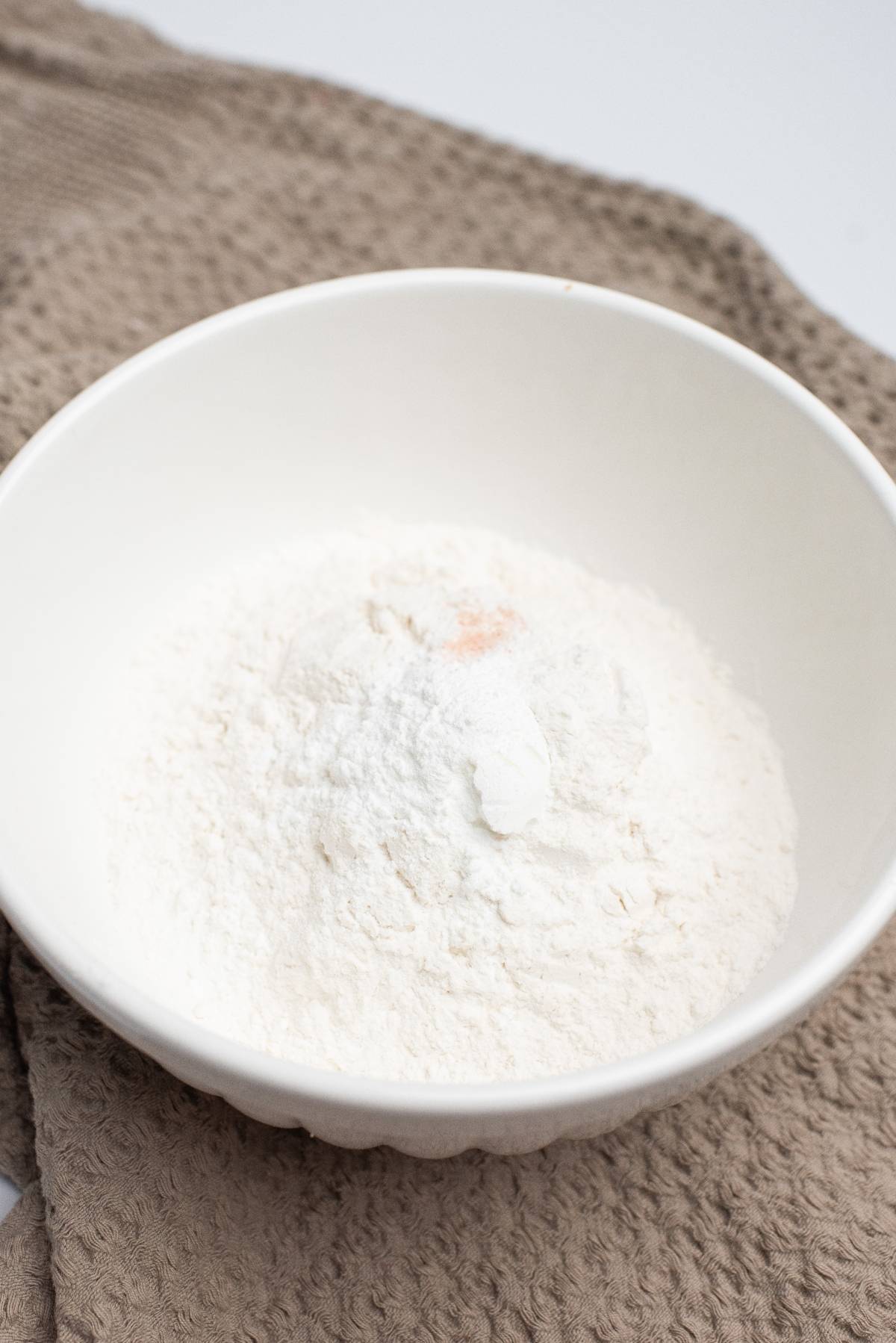 A white bowl filled with flour and a pinch of salt, resting on a beige textured cloth—the perfect start for an easy blondie recipe or classic blondie bars.