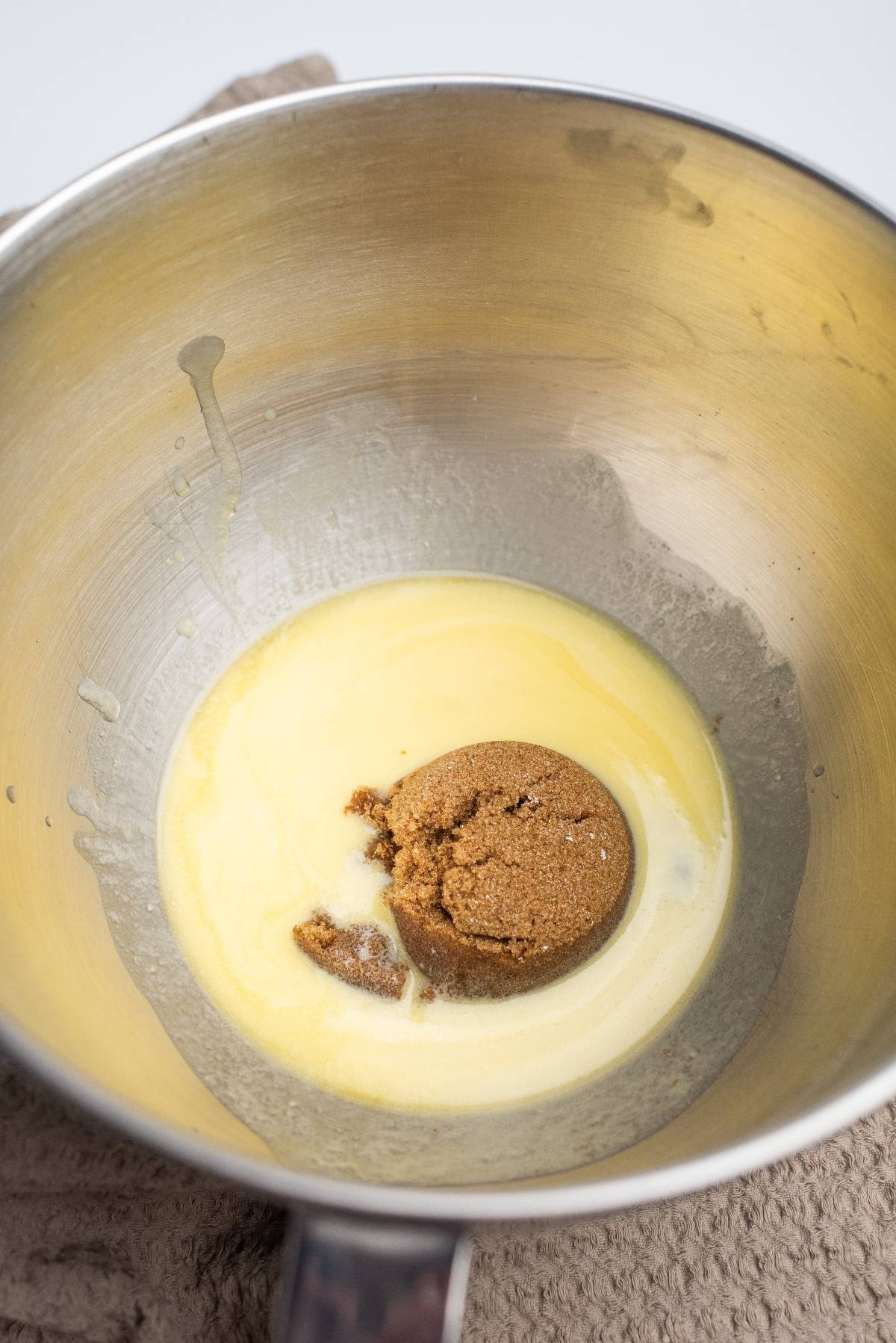 Melted butter and brown sugar in a metal mixing bowl, perfect for starting an easy blondie recipe, placed on a beige cloth.
