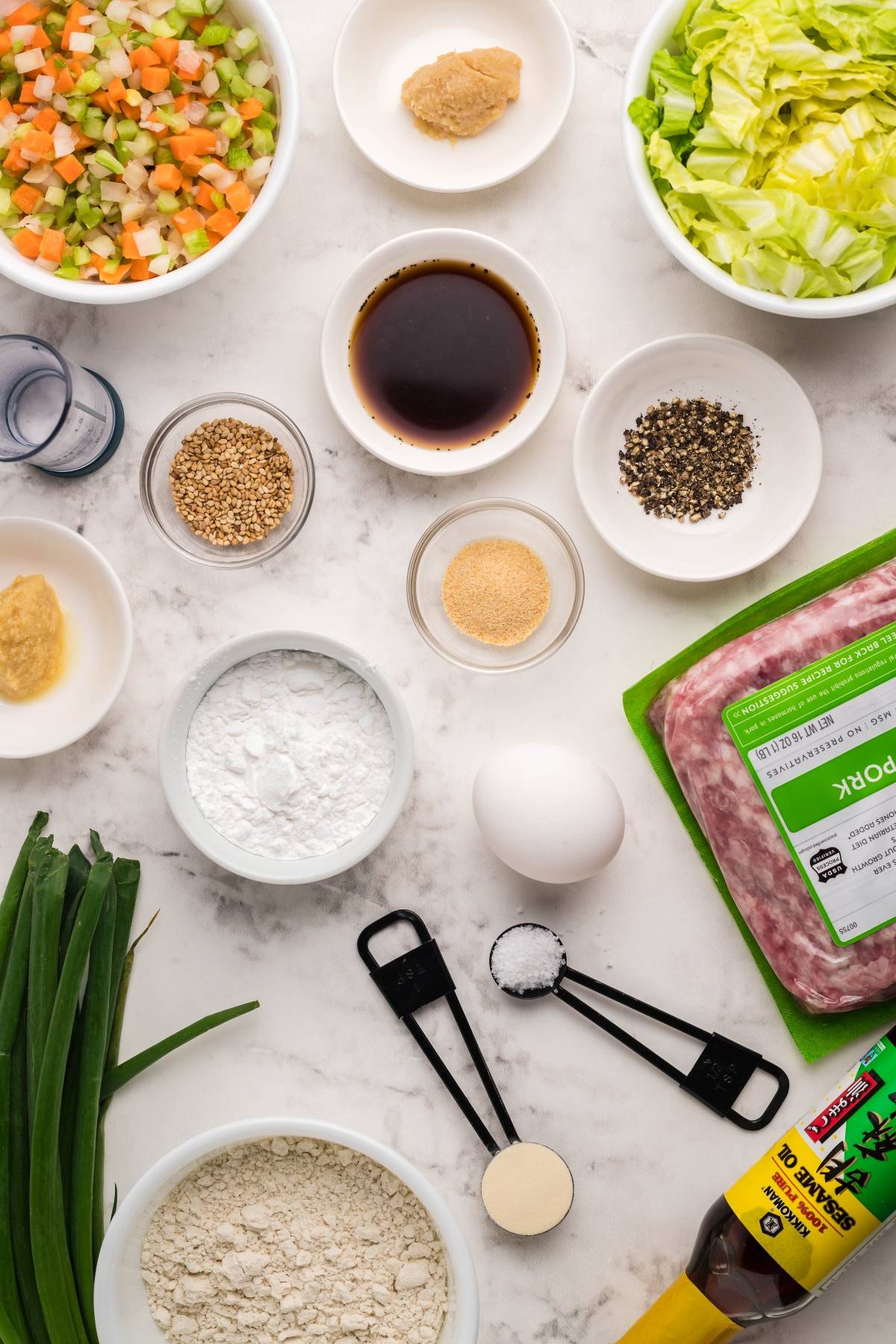 Ingredients for gluten free potstickers, including ground pork, cabbage, egg, gluten-free flour, sauces, spices, and chopped veggies—perfect for an Asian-style dish.
