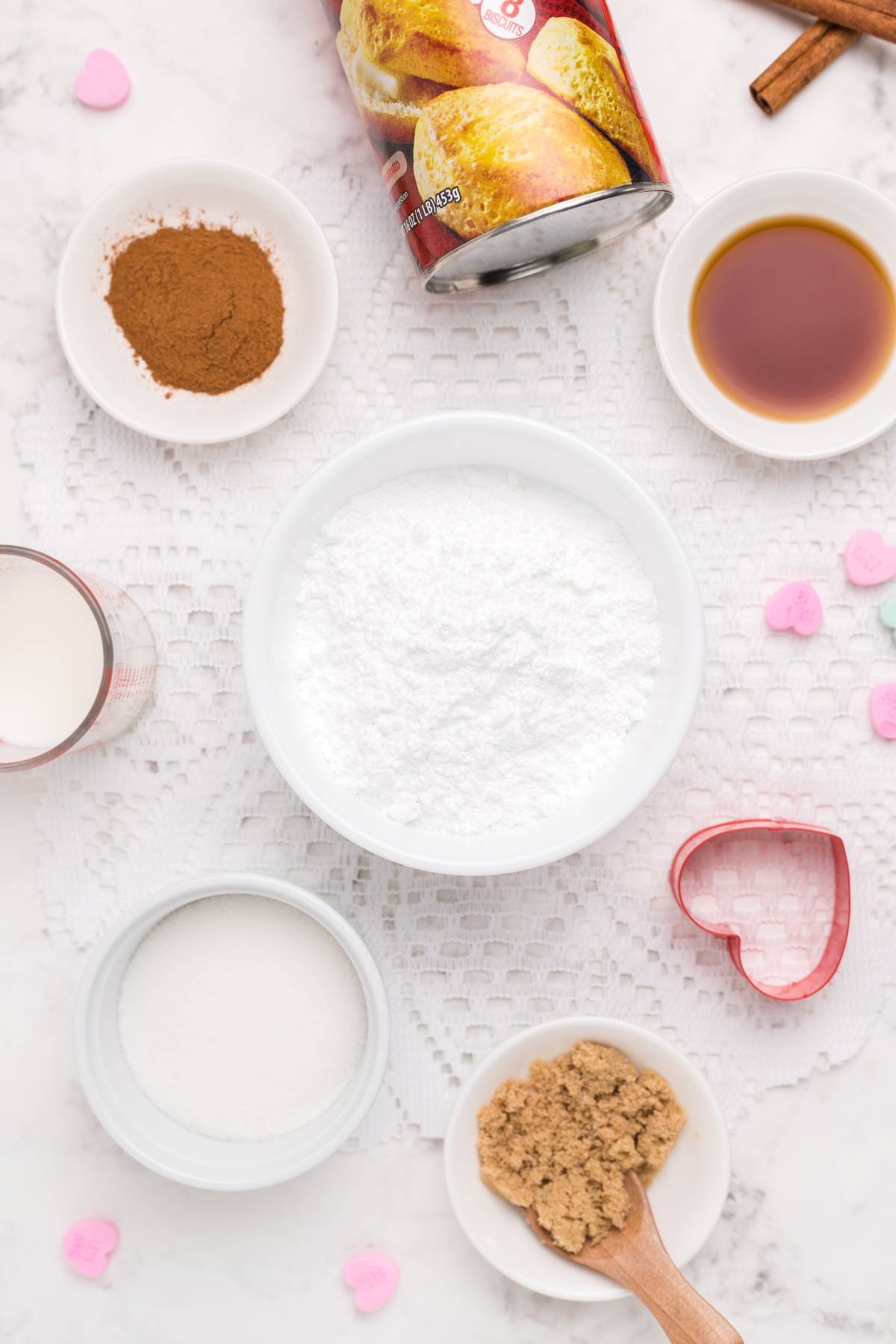 Baking ingredients in bowls on a white cloth, including powdered sugar, brown sugar, cinnamon, and vanilla—perfect for trying a mini doughnut recipe or mastering a fun cinnamon roll hack.