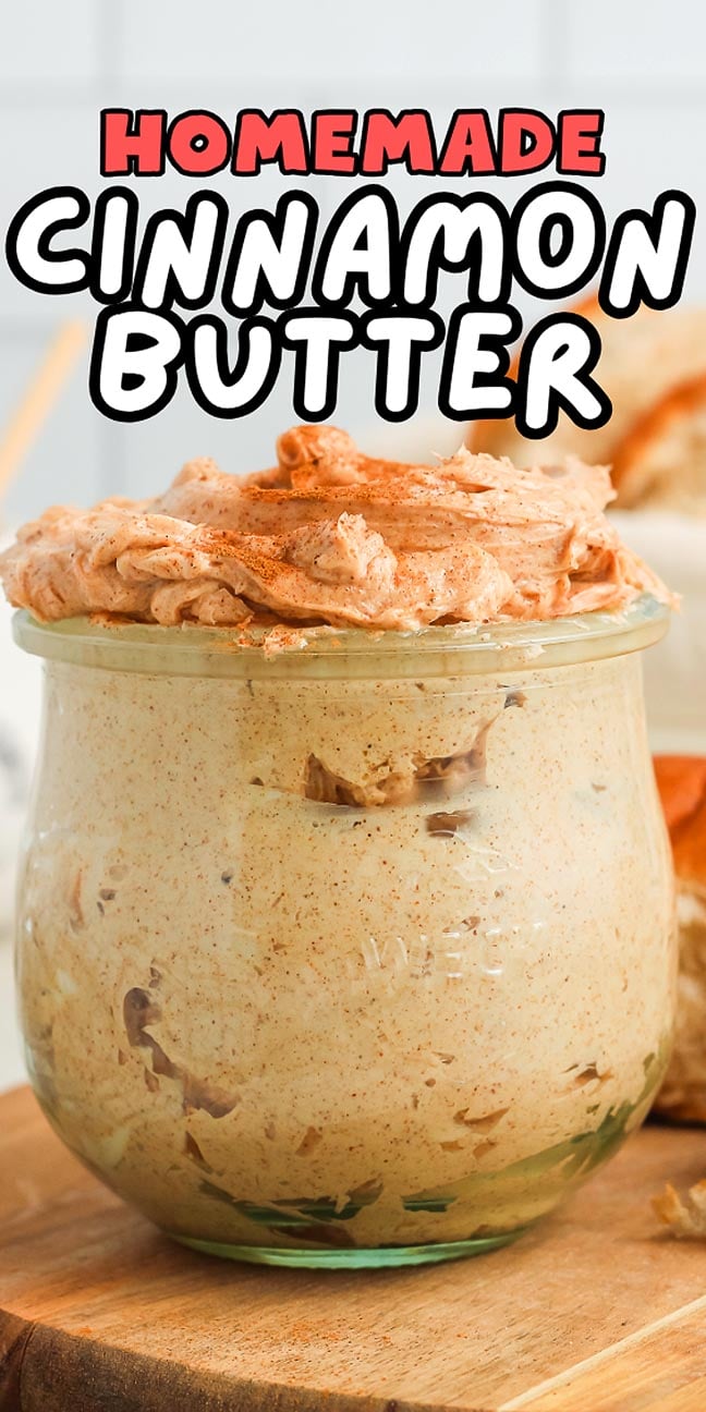 A glass jar filled with rich, homemade cinnamon butter, topped with a generous swirl, sits invitingly on a wooden surface.