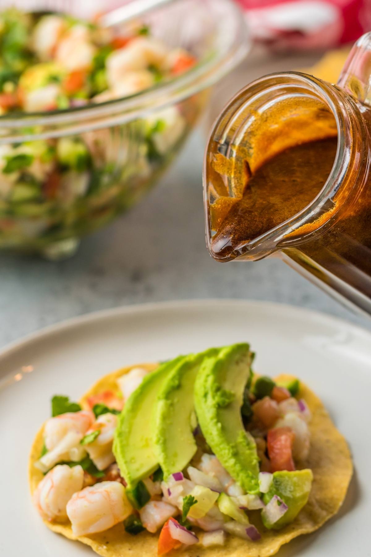 Tostada topped with shrimp ceviche and avocado slices, finished with a drizzle of homemade Unagi sauce for an extra punch of flavor.