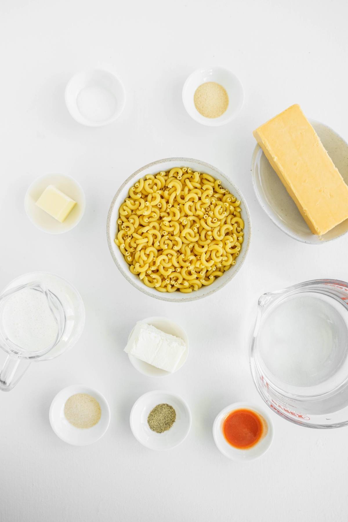 Macaroni, cheese, butter, milk, cream cheese, hot sauce, and seasonings arranged on a white surface—perfect for an Easy instant pot pasta recipe or classic Mac and cheese.